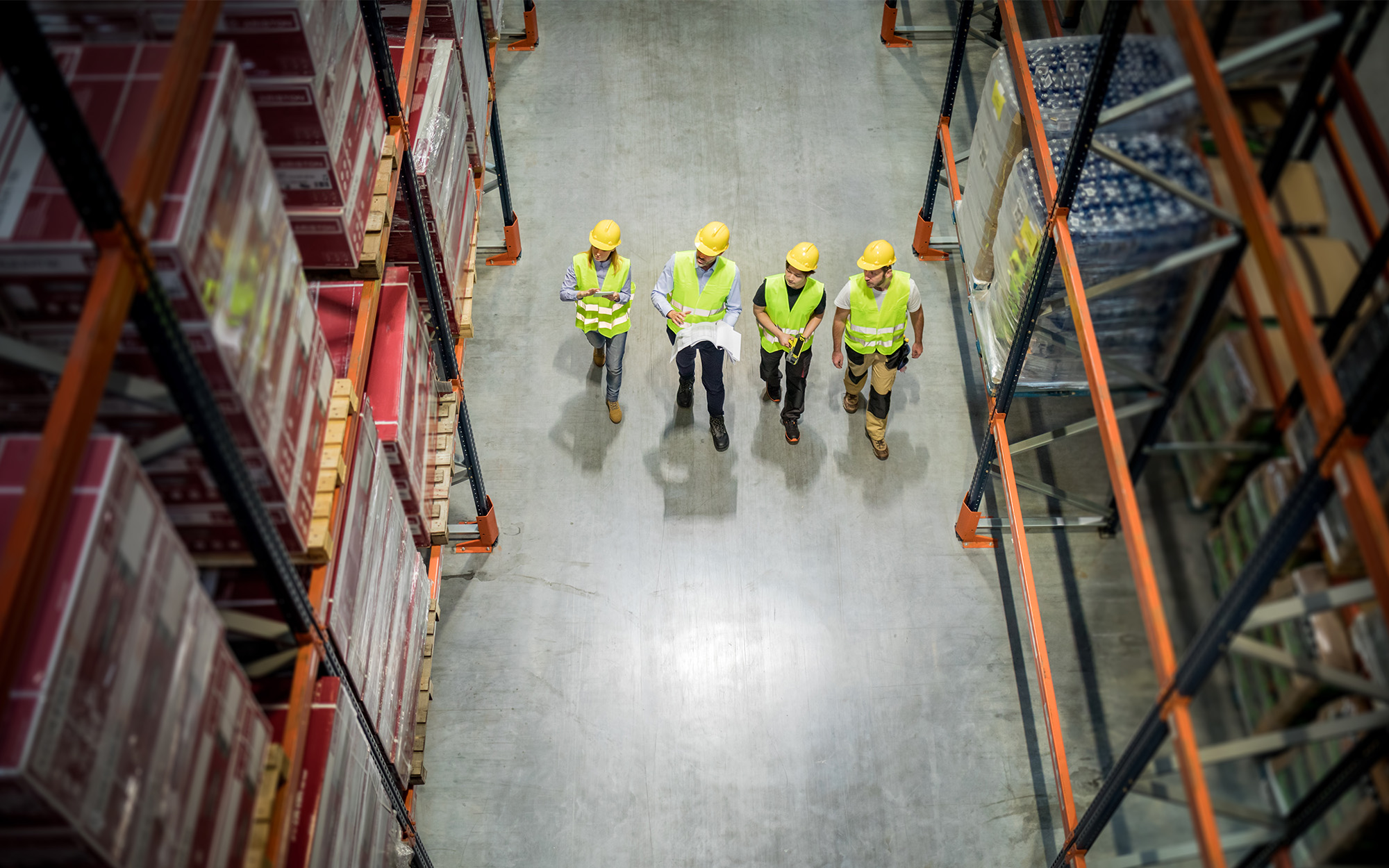 Warehouse workers at work between rows of tall shelves full of packed boxes